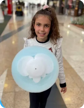 Smiling young guest enjoying pink cotton candy from a Funland Vending machine, UAE